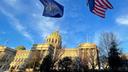 The Pennsylvania and American flags flutter in front of the Capitol building in Harrisburg.