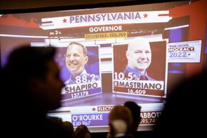 Early results for the governor’s race appear on screen at Doug Mastriano’s election night watch party in Camp Hill, PA.